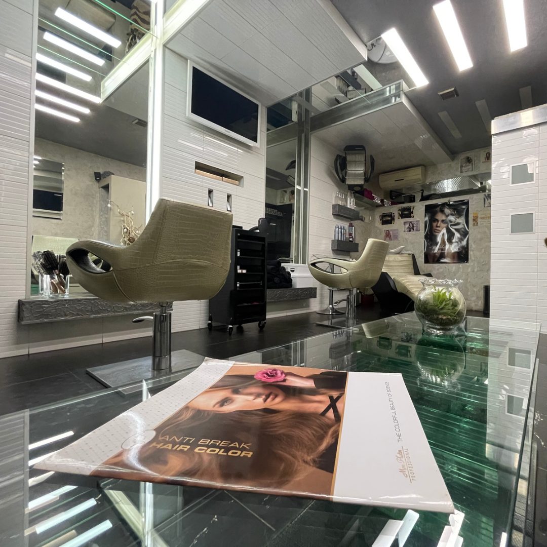 Interiér salónu HAIR STUDIO: kožené kreslá pri zrkadlách a sklenený stolík so vzorkovníkom farieb